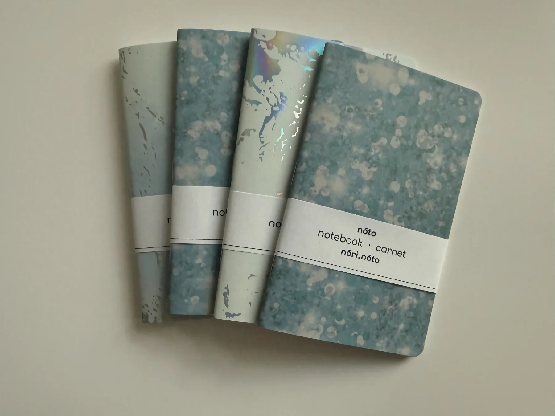 Four creative-paper Nōto notebooks arranged without packaging hands